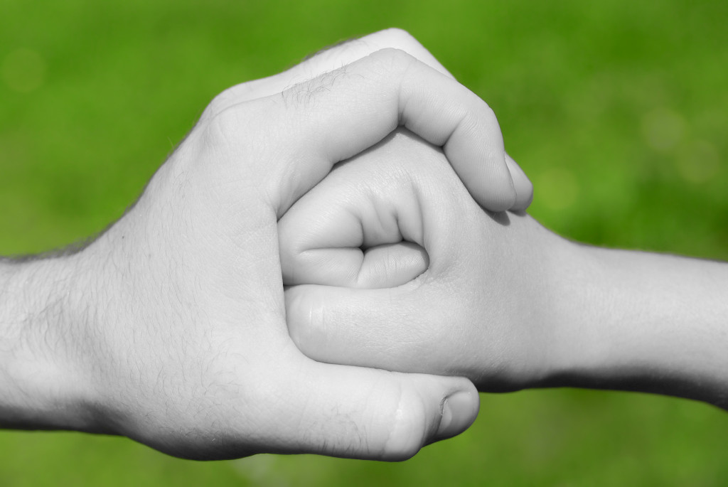black and white hand holding fist in front of green background